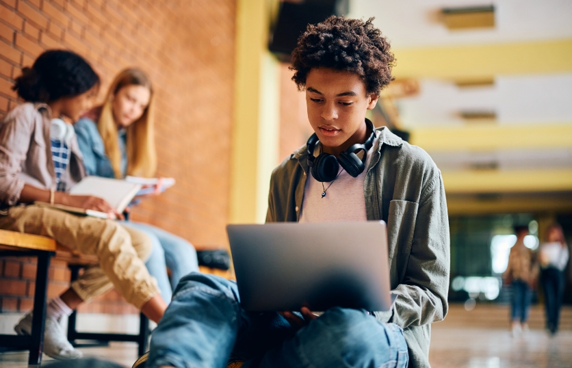 A young man with headphones and a laptop, engaged in online learning.