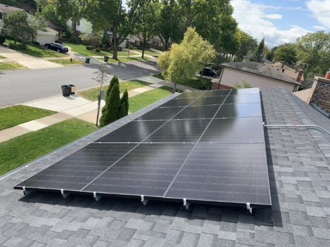 An aerial view of a residential solar system on a hip roof style.