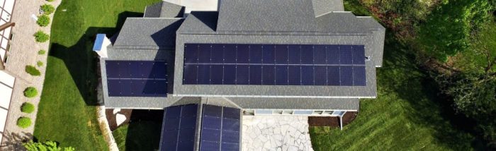 A large modern home with solar panels across four different roof planes.