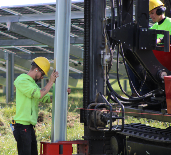 Commercial solar installer working on setting a metal beam in the ground.