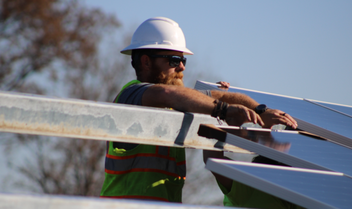 Commercial solar installer working on setting a solar module. 