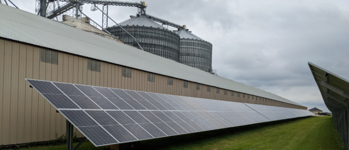 Large scale grain bin storage facility with sectioned solar arrays installed on the metal roof. 